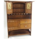 AN ARTS AND CRAFTS OAK DRESSER with open shelves, flanked by embossed inset brass panels and
