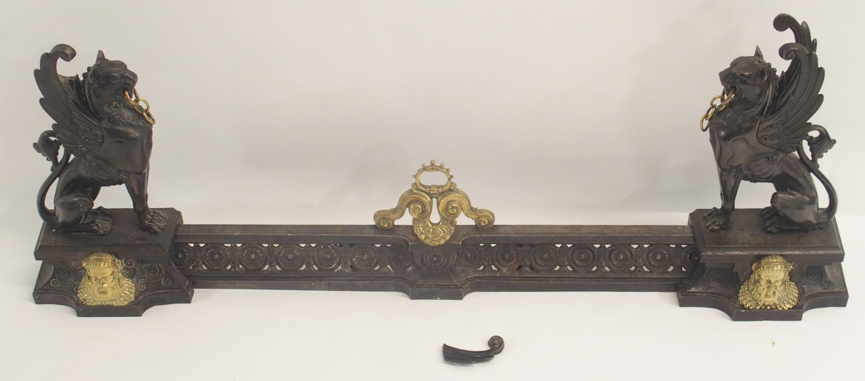 A 19TH CENTURY CAST STEEL AND BRASS FIREPLACE FENDER in three sections, modelled with winged