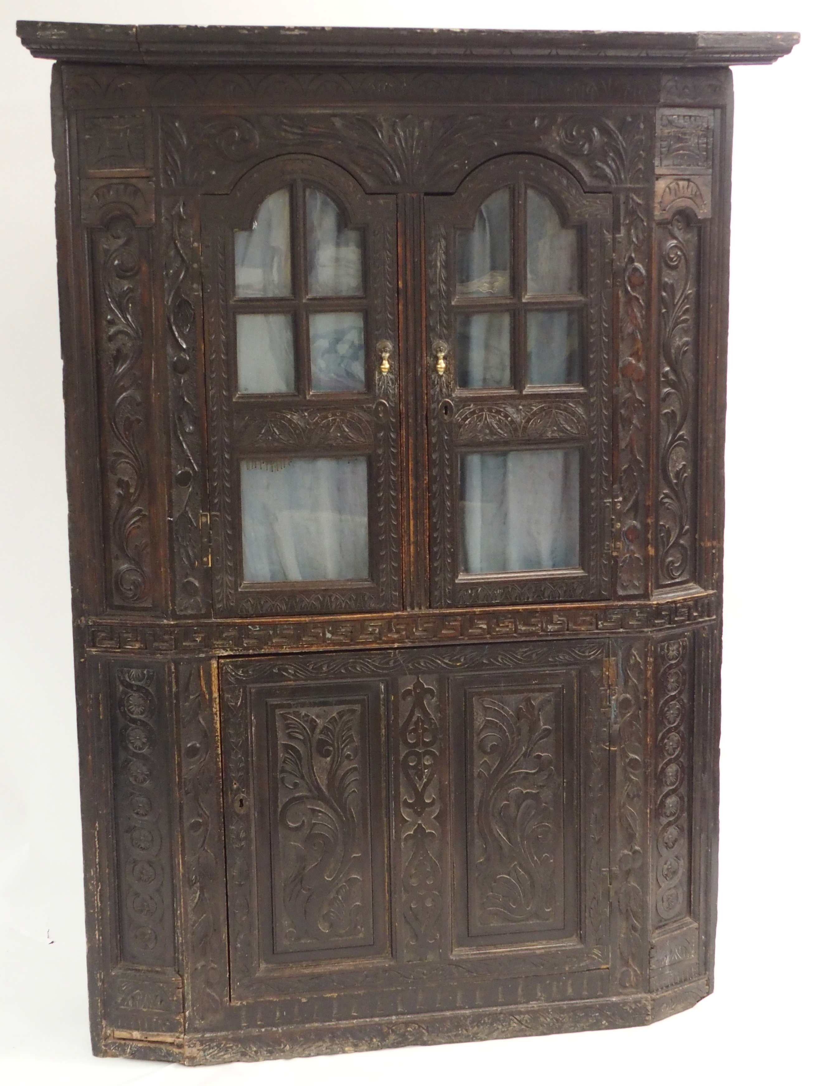 A VICTORIAN STAINED OAK CORNER DISPLAY CABINET carved allover with scrolling foliage, with a pair of