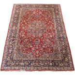 A RED GROUND KESHAN RUG with central medallion, matching spandrels and border, 404cm x 300cm