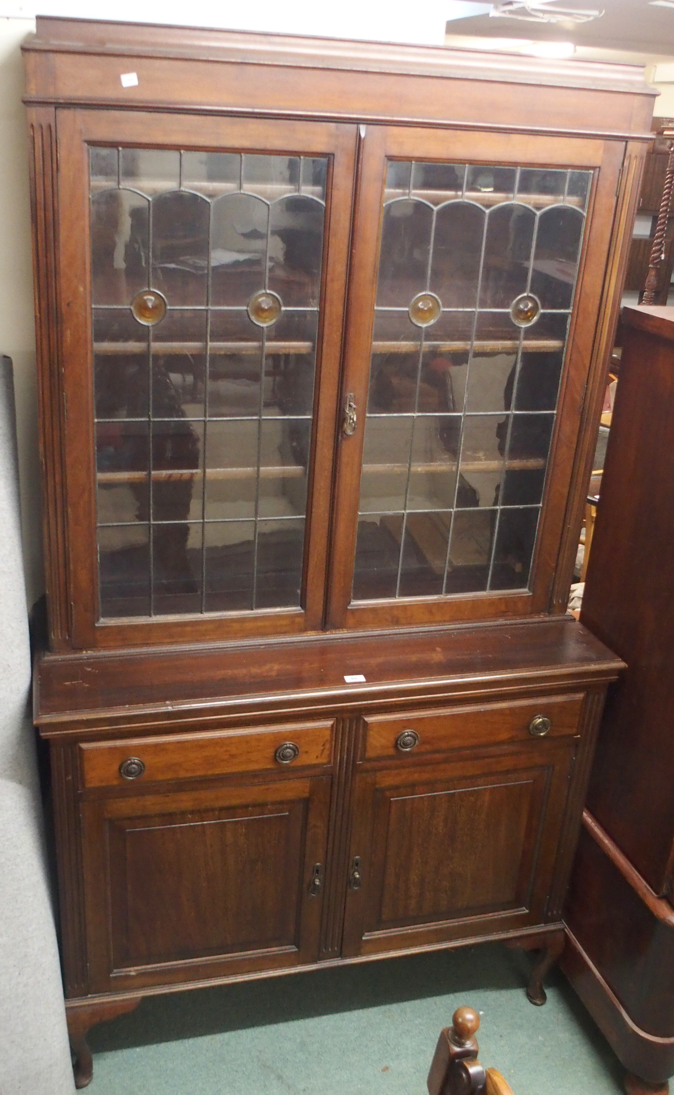 A mahogany bookcase with leaded and stained glass doors over a base with two drawers over two