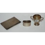 A lot comprising a small silver trophy cup, napkin ring, and cigarette case, 259gms Condition