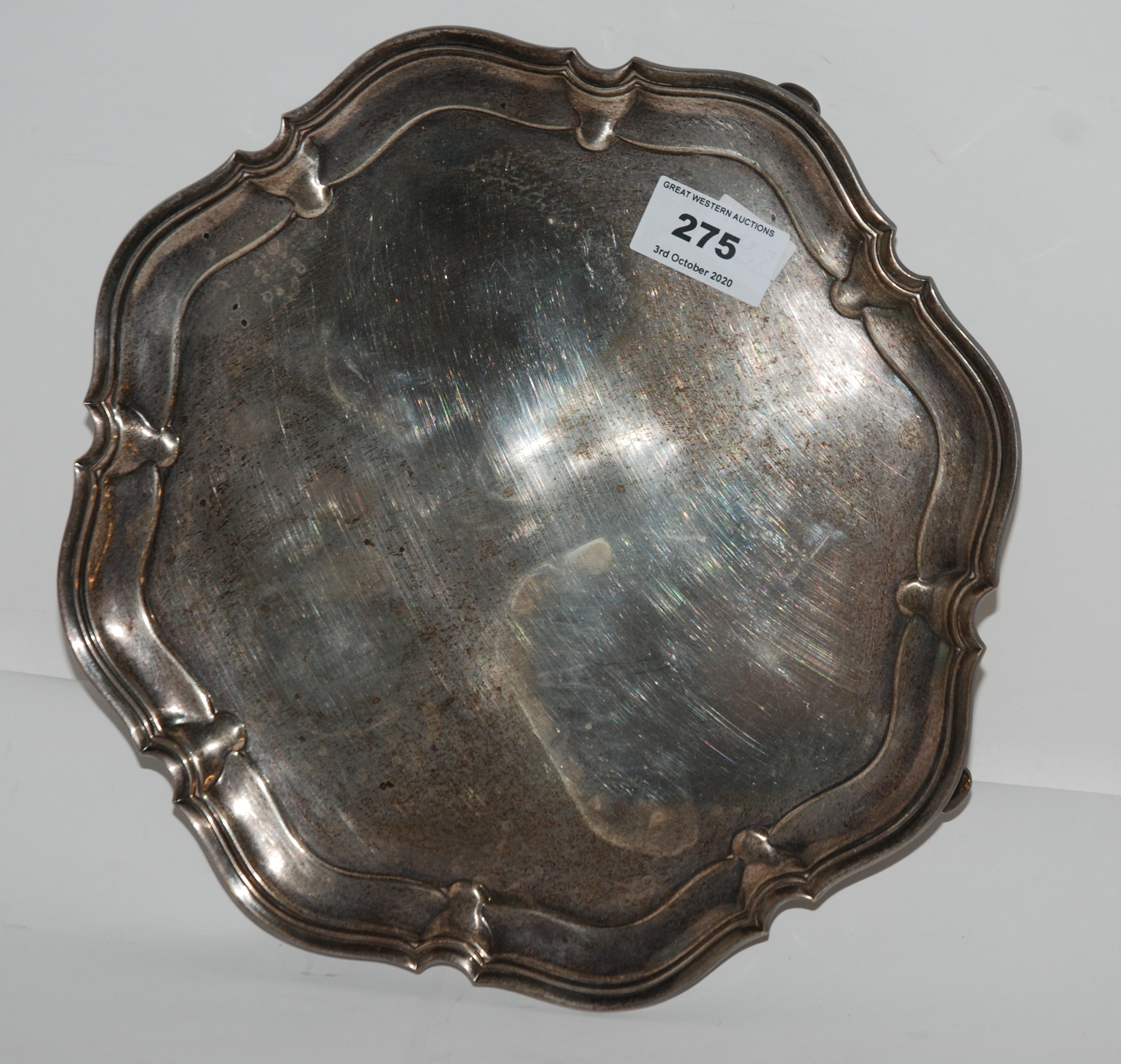 A silver card tray, Sheffield 1930 of circular form with scalloped edges on four out swept feet,