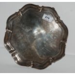 A silver card tray, Sheffield 1930 of circular form with scalloped edges on four out swept feet,