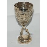 An Indian white-metal trophy goblet, the bowl embossed with village scenes, the cartouche