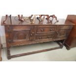 An oak sideboard with two drawers flanked by two carved doors on stand, 84cm high x 167cm wide x