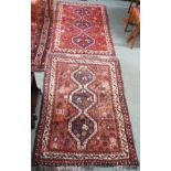 A red ground Eastern rug with three central lozenges, 153cm x 98cm and a dark pink ground rug ,140cm