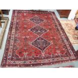 A red ground Eastern rug with three central lozenges with stylized animals and birds, 284cm x