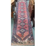 A red ground runner with seven central lozenges, 284cm x 71cm Condition Report: Available upon