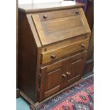 An oak bureau with single drawer over two cupboard doors Condition Report: Available upon request