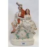 A pottery flatback of a Scottish man and woman sitting above a clock Condition Report: Available