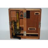 A brass student microscope in fitted case and box of slides (2) Condition Report: Available upon