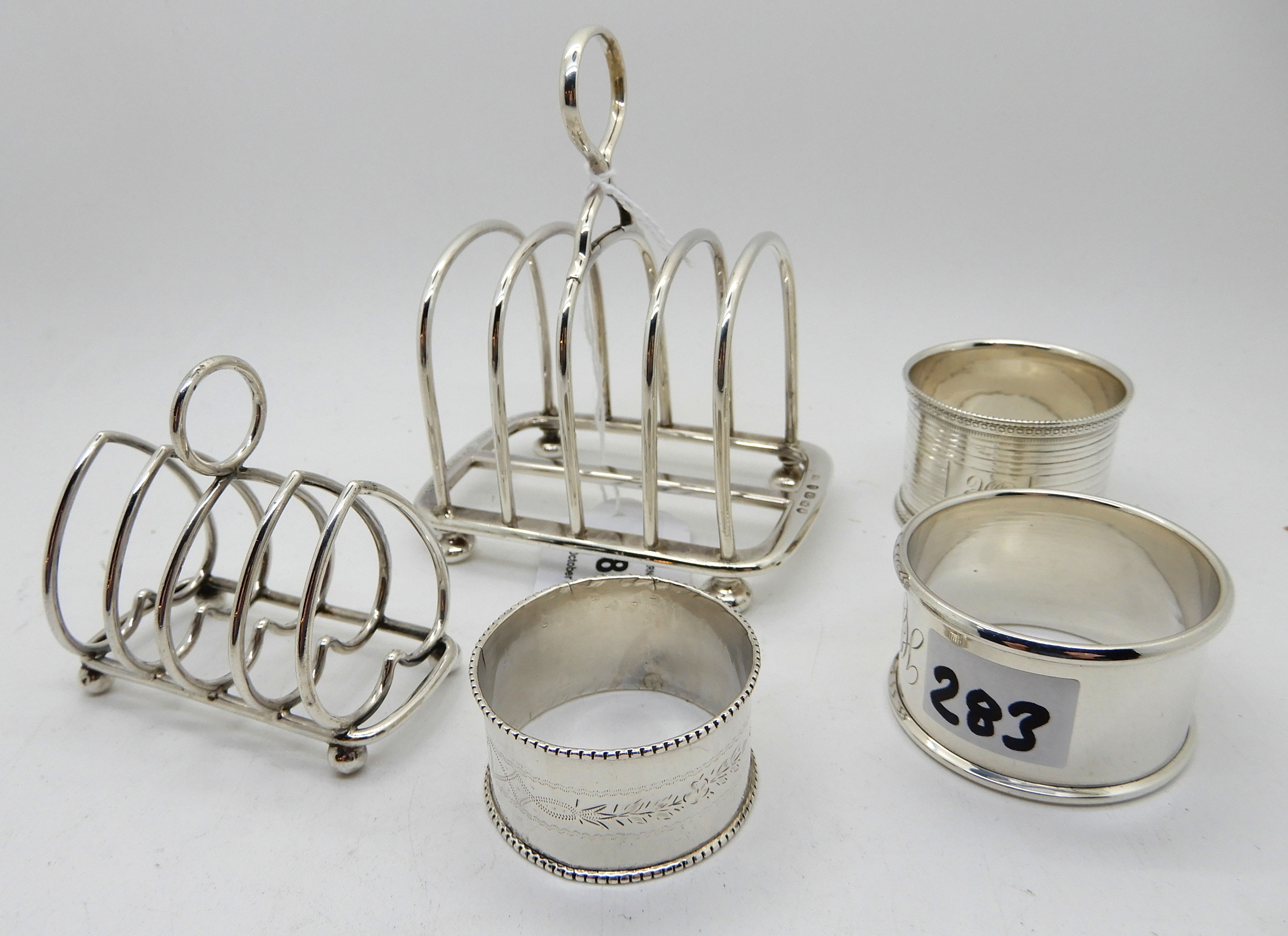 A lot comprising two silver toastracks, Birmingham marks and three silver napkin rings, assorted