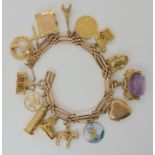A 15ct gold charm bracelet with nine 9ct charms to include an amethyst fob, three 14k charms, one