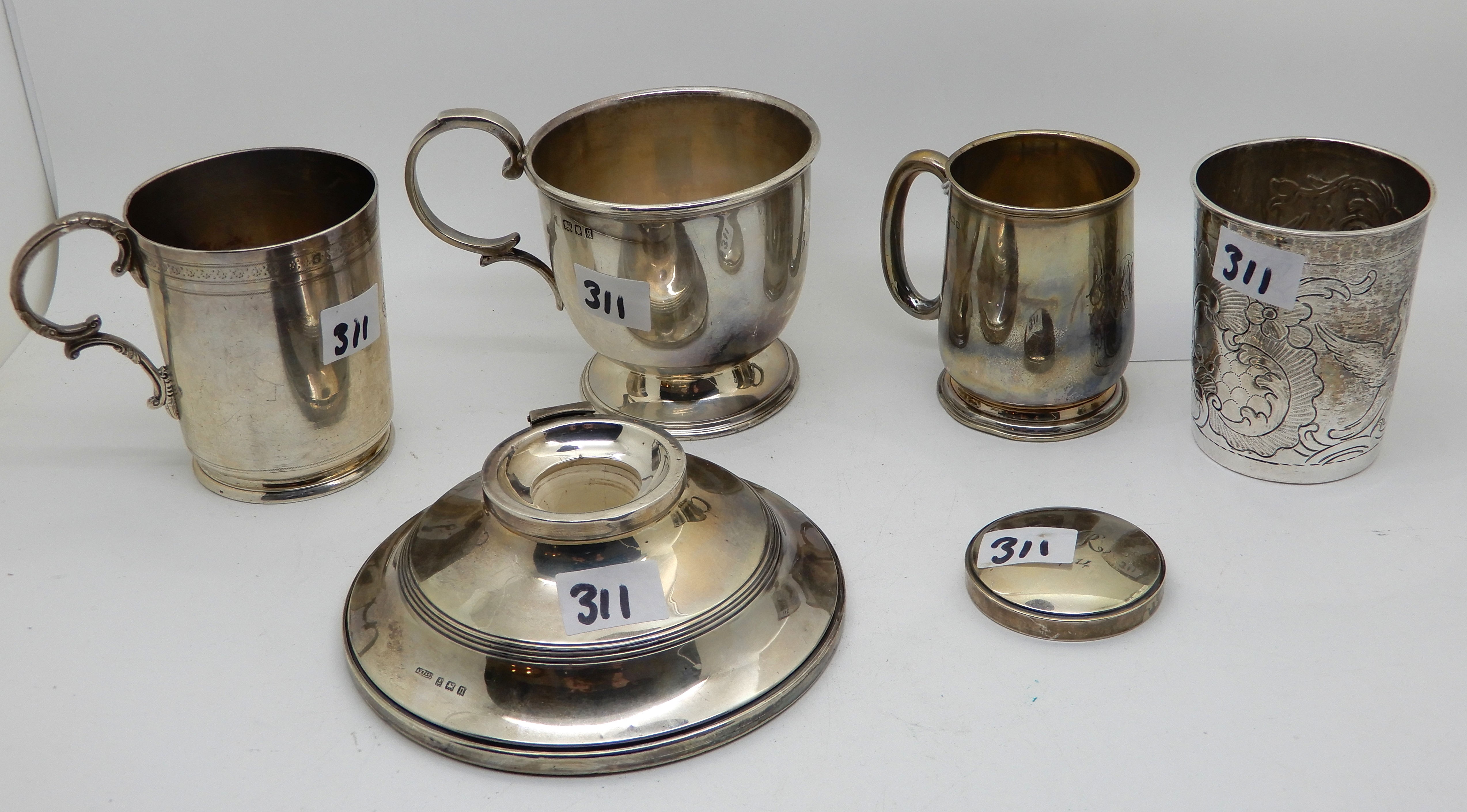 A lot comprising two silver mugs, London 1933, Birmingham 1925, a silver beaker, an inkwell (def)