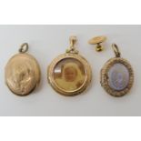 A yellow metal photo locket together with two other vintage lockets and a rolled gold tie stud,