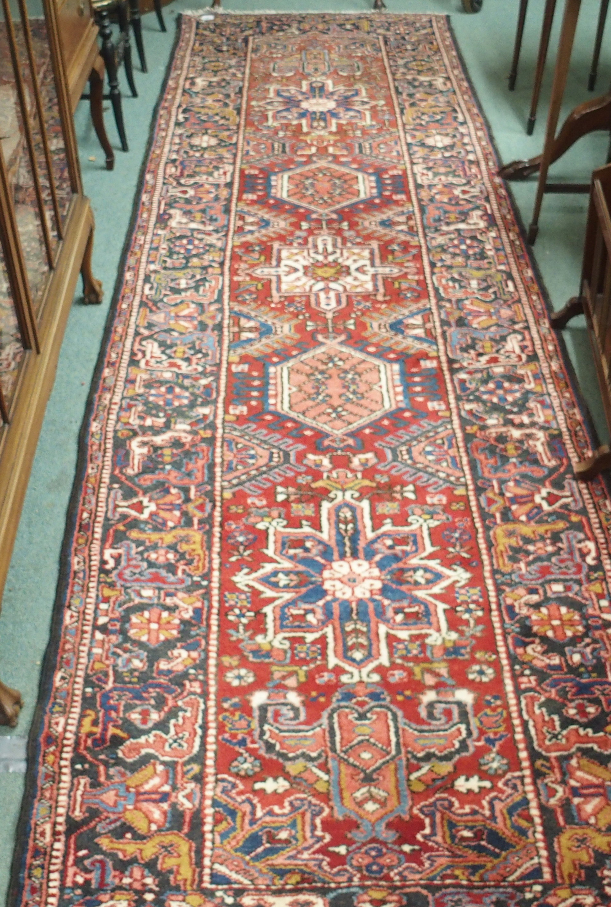 A red ground Karejeh runner with five central lozenges, 356cm x 104cm Condition Report: Available