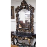 An ornate black and gilt console table, 83cm high x 130cm wide x 53cm deep and mirror, 165cm high