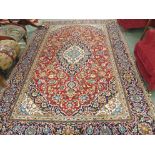 A red ground Keshan rug with blue central medallion with matching spandrels and a blue border, 302cm