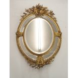 A LOUIS XVI STYLE GILTWOOD AND GESSO OVAL WALL MIRROR with birds and musical trophy surmount above