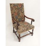 A 17TH CENTURY STYLE WALNUT ARMCHAIR with woolwork upholstered covers, joined by carved acanthus