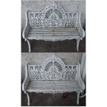 A PAIR OF CAST IRON VICTORIAN STYLE GARDEN BENCHES decorated with stylised foliage and on splayed