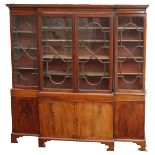 A MAHOGANY BREAKFRONT BOOKCASE the overhanging cornice above four glazed astragal doors, enclosing