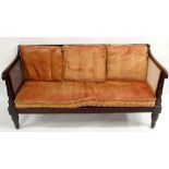 A VICTORIAN EBONISED BERGERE SETTEE the reeded back rail above scroll arms and on tapering legs,