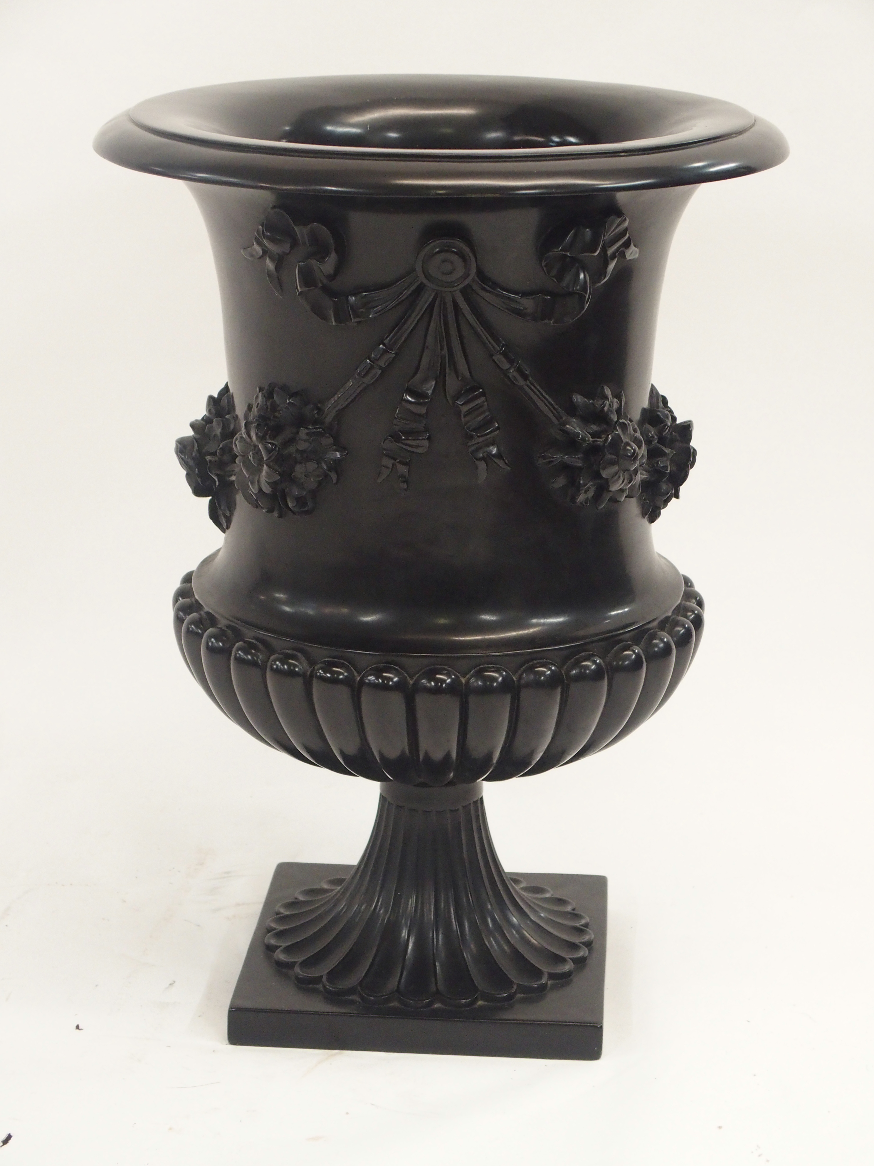 A COMPOSITE CLASSICAL STYLE URN cast with ribbon tied garlands of flowers above a lobed socle,