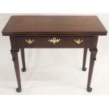 A GEORGE III MAHOGANY FOLD OVER TEA TABLE the hinged top above a drawer on leaf capped tapering legs