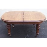 A VICTORIAN OAK OVAL EXTENDING DINING TABLE on turned baluster and fluted legs on brass feet with