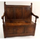 AN OAK HALL SETTLE the triple panelled back with dentil frieze above scroll arms and a hinged