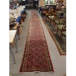 A VERY LARGE RED GROUND EASTERN RUNNER with allover geometric design, 1050cm x 79cm Condition