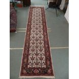 A CREAM GROUND RUNNER WITH STYLISED FLOWERS in a blue and red border, 380cm x 90cm Condition Report: