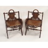 A PAIR OF VICTORIAN OAK HALL CHAIRS each carved with a shield back and pierced scrolls with loop