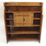 AN ARTS AND CRAFTS OAK OPEN BOOKCASE with six shelves divided by a pair of hinged doors, fitted with