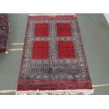 AN EASTERN RUG WITH FOUR MAIN RED PANELS, with geometric borders,and a signature 184cm x 120cm