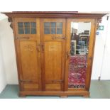 AN EARLY 20TH CENTURY OAK ARTS AND CRAFTS TRIPLE DOOR WARDROBE