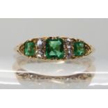 AN 18CT GOLD EMERALD AND DIAMOND RING IN A SCROLLED MOUNT hallmarked Chester 1903, largest emerald