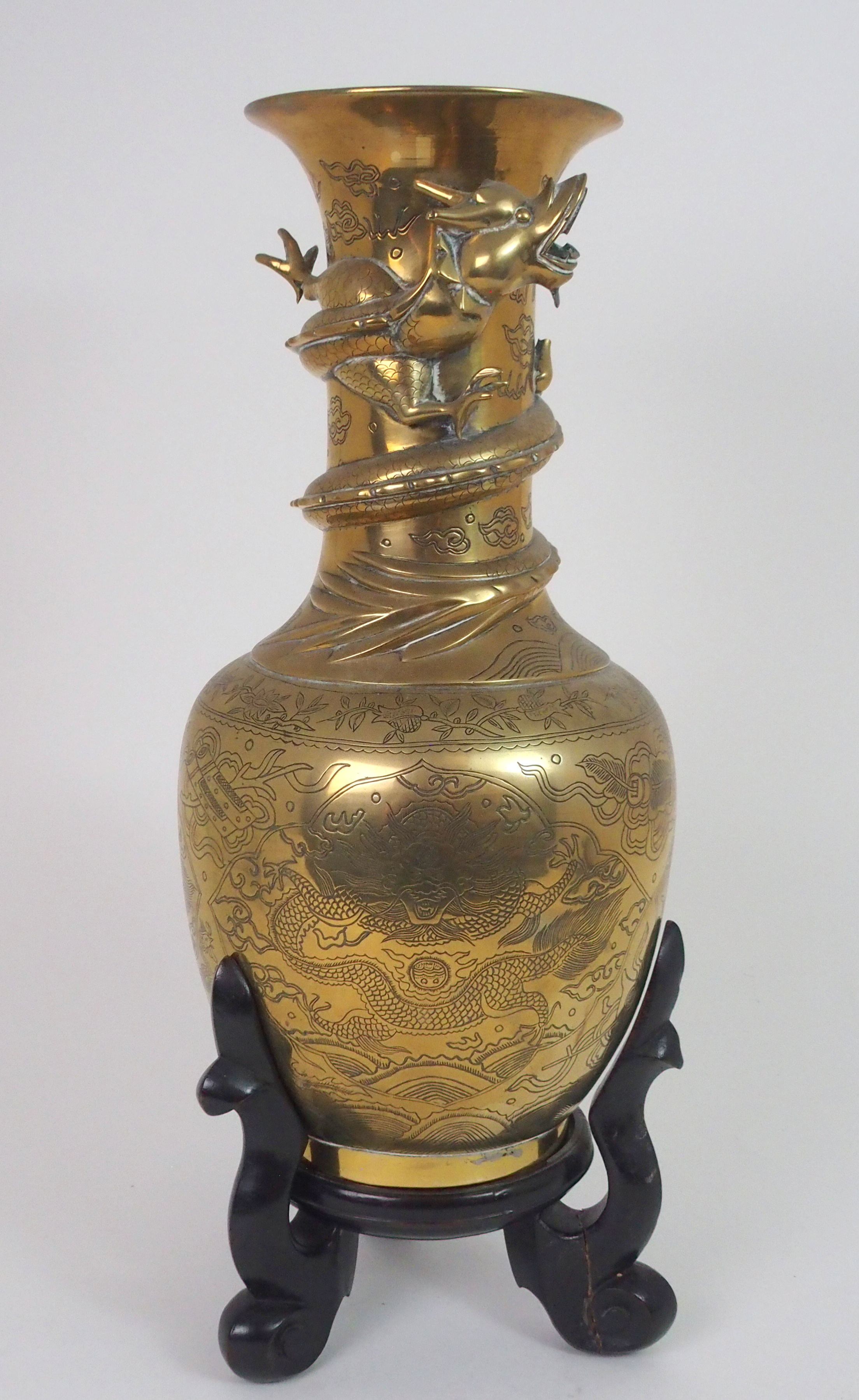 A CHINESE BRASS BALUSTER VASE cast with a dtragon wraped around the neck and above panels of dragons