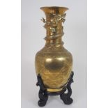 A CHINESE BRASS BALUSTER VASE cast with a dtragon wraped around the neck and above panels of dragons