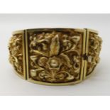 A GILDED WHITE METAL REPOUSSE INDIAN BANGLE with scenes of flowers and fruit. Width at widest