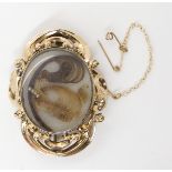 A HAIR LOCKET BACK MOURNING BROOCH with a yellow metal scrolled and foliate frame. dimensions 4.