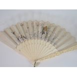A CANTONESE IVORY AND SILK FAN woven with birds and foliage, the ends carved with numerous figures