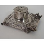 A CHINESE SILVER INK STAND decorated with irises and foliage, surrounding a hinged circular well,