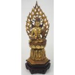 AN ASIAN GILT BRONZE MODEL OF BUDDHA seated on a high lotus throne, with pierced flaming aura,