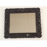 A CHINESE HARDWOOD WALL MIRROR the pierced frame carved with dragons chasing the flaming pearl of