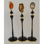 A SET OF THREE COTEMPORARY SCULPTURES each modelled as a black stand holding a slither of agate,