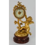 A GILDED METAL TIMEPIECE modelled as a cherub holding aloft the clock, which is mounted with birds