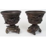 A PAIR OF CHINESE BRONZE JARDINIERES ON STANDS cast with dragons on a raging sea, beneath key